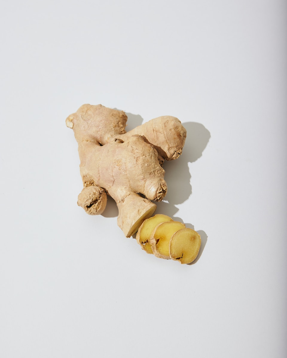a ginger root and a piece of ginger on a white surface